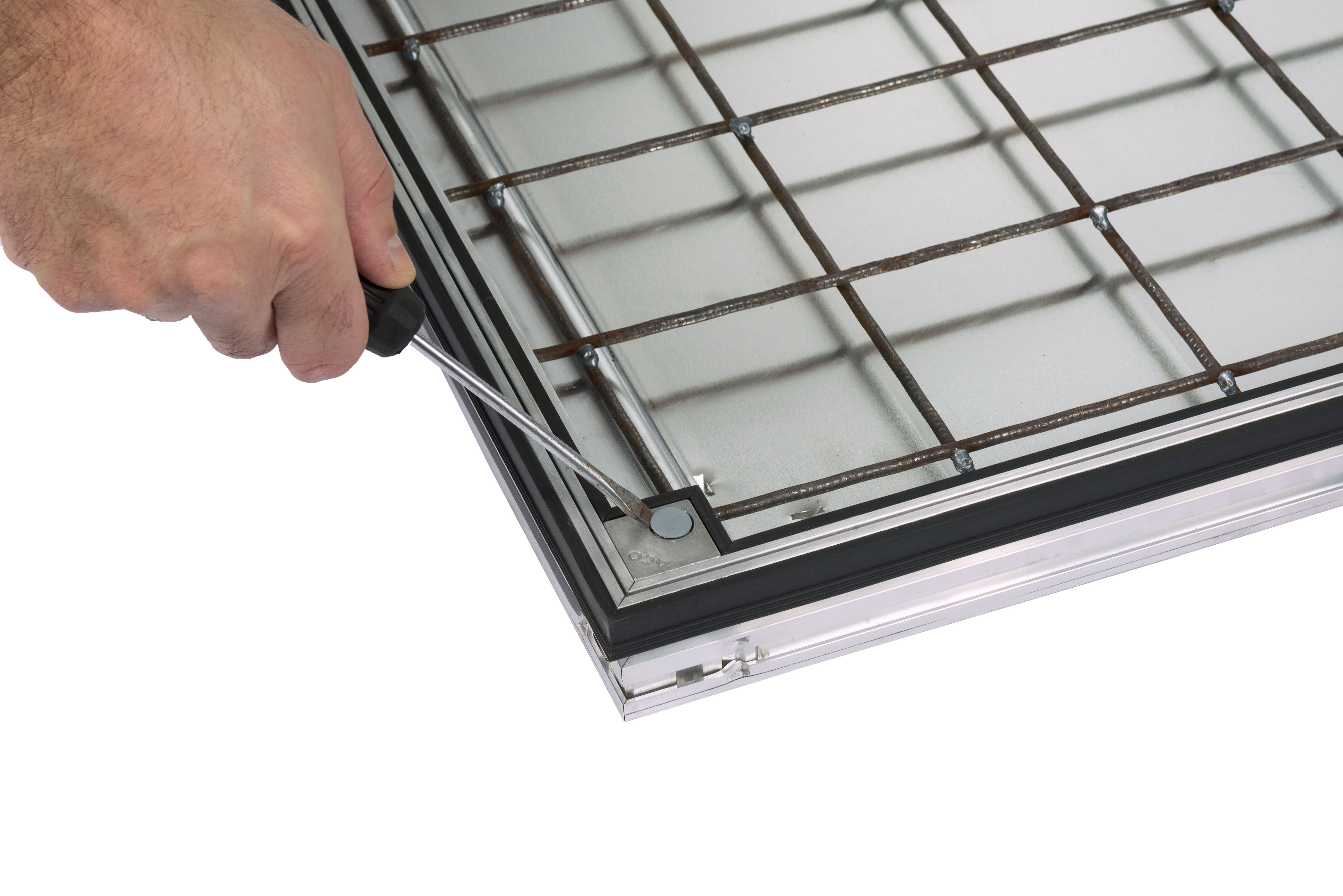 A close-up of a hand using a screwdriver to adjust a corner locking mechanism on the ACO UniFace AL Shallow vinyl cover.