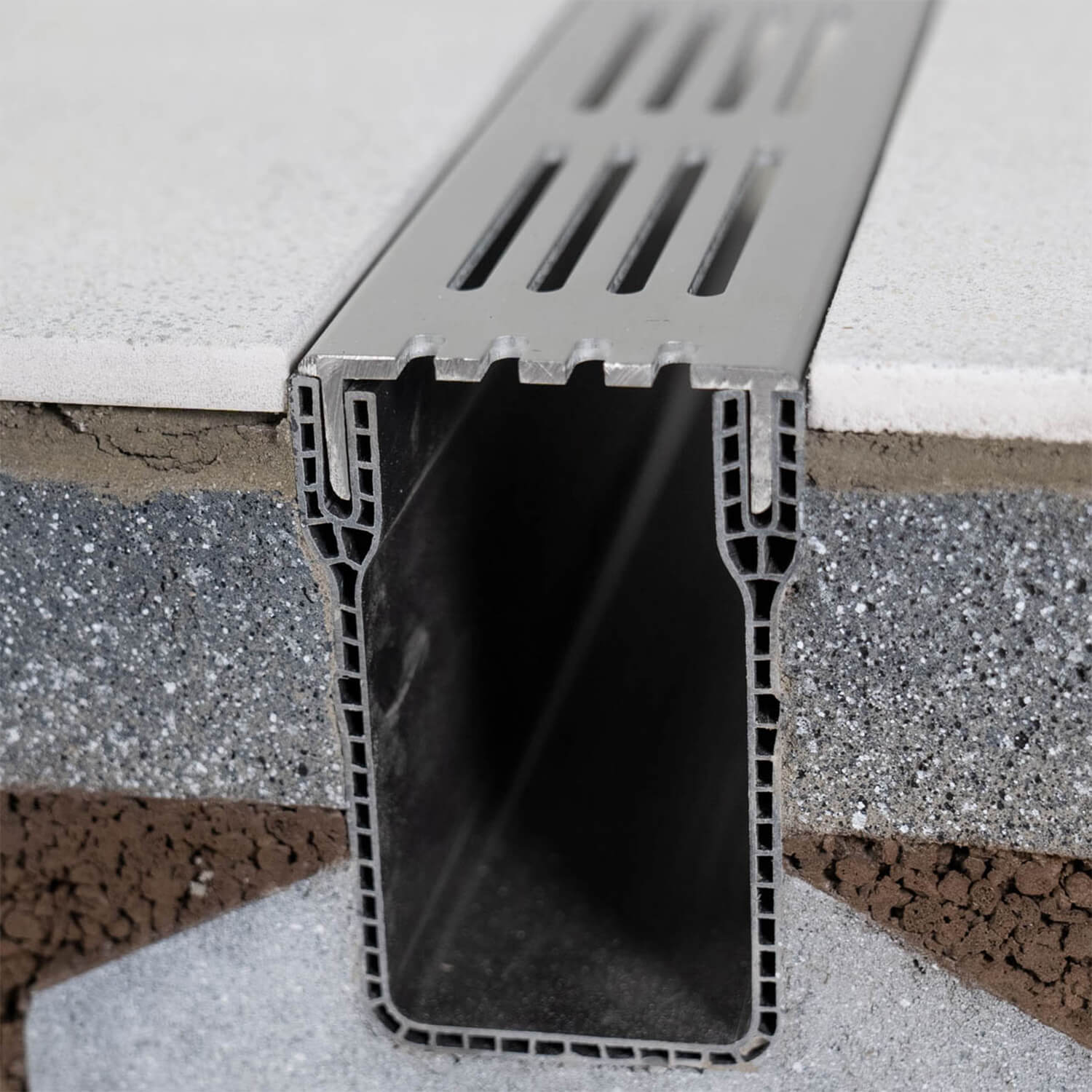 Metal drainage channel embedded in concrete with a textured background