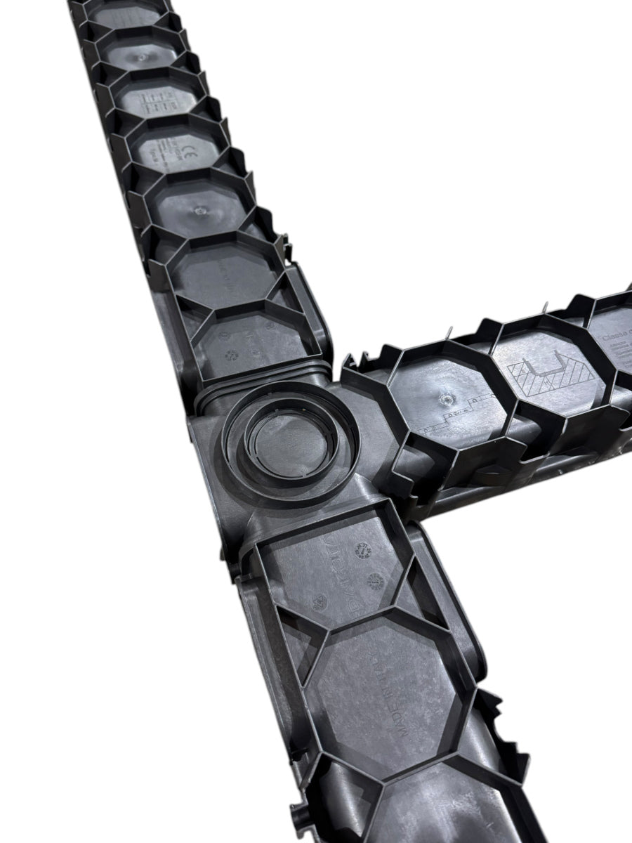 A close-up, overhead view of the underside of two channel drain sections joined to create a right-angle turn.