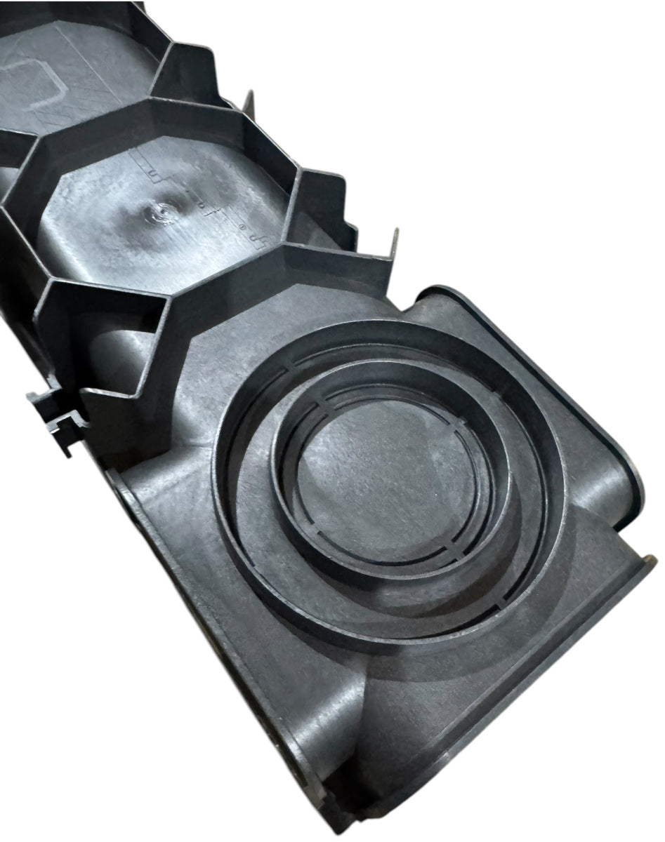 A close-up of a channel drain end piece, showing the circular outlet and the hexagonal pattern on the underside.