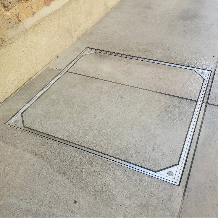 Square manhole cover on a concrete pavement