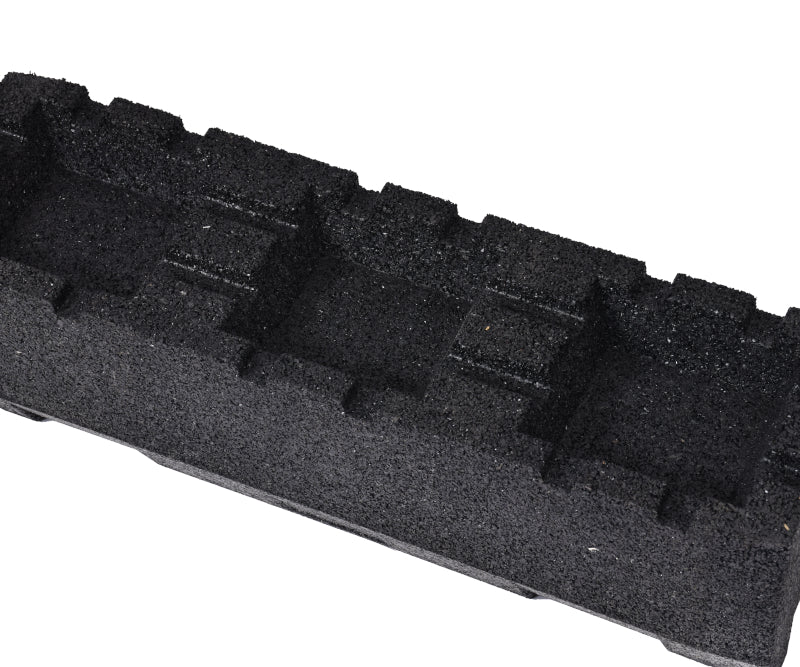 A close-up view of the underside of a black, textured rubber mounting block, highlighting the longitudinal grooves designed for stability and drainage.